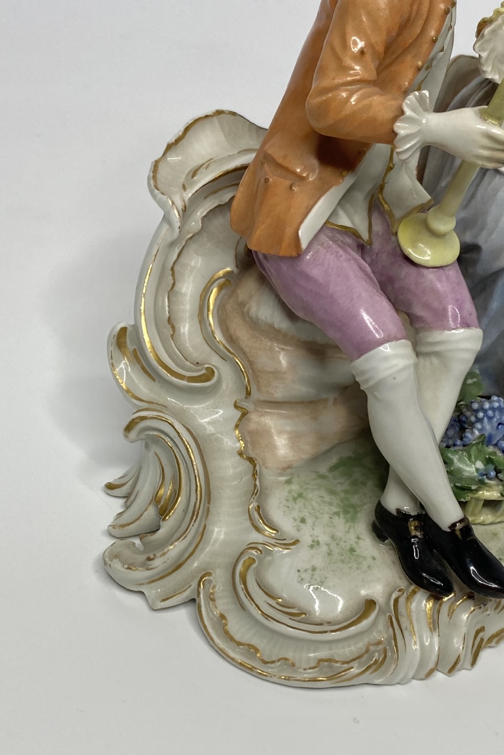 An eighteenth-century Ludwigsburg polychrome porcelain figurine group featuring a man with a wind instrument and a woman seated on a gilded rococo scroll base. View XIII