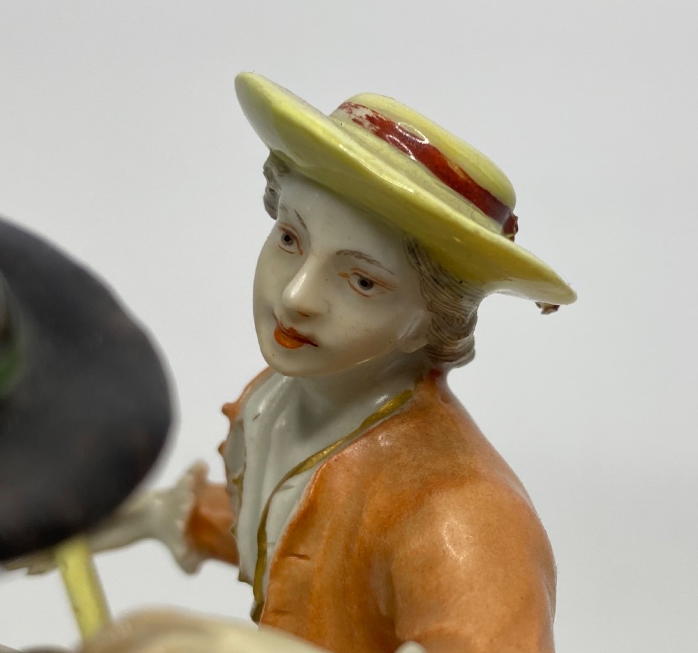 An eighteenth-century Ludwigsburg polychrome porcelain figurine group featuring a man with a wind instrument and a woman seated on a gilded rococo scroll base. View XIV