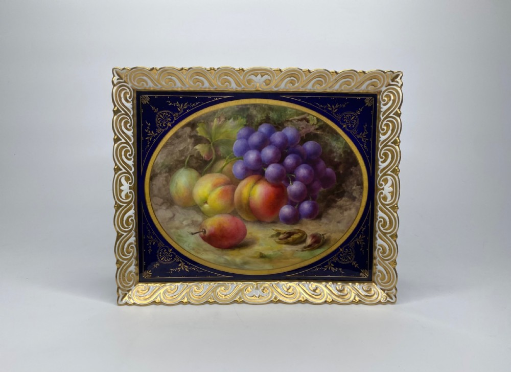 A square Royal Worcester porcelain tray featuring a central oval hand-painted fruit study framed by a dark cobalt blue ground with gold tooling and a pierced gilt scrollwork border.
