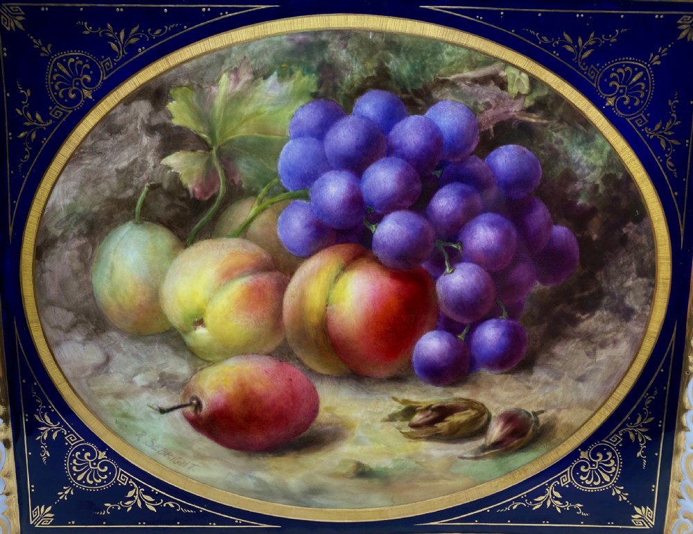A square Royal Worcester porcelain tray featuring a central oval hand-painted fruit study framed by a dark cobalt blue ground with gold tooling and a pierced gilt scrollwork border. View II