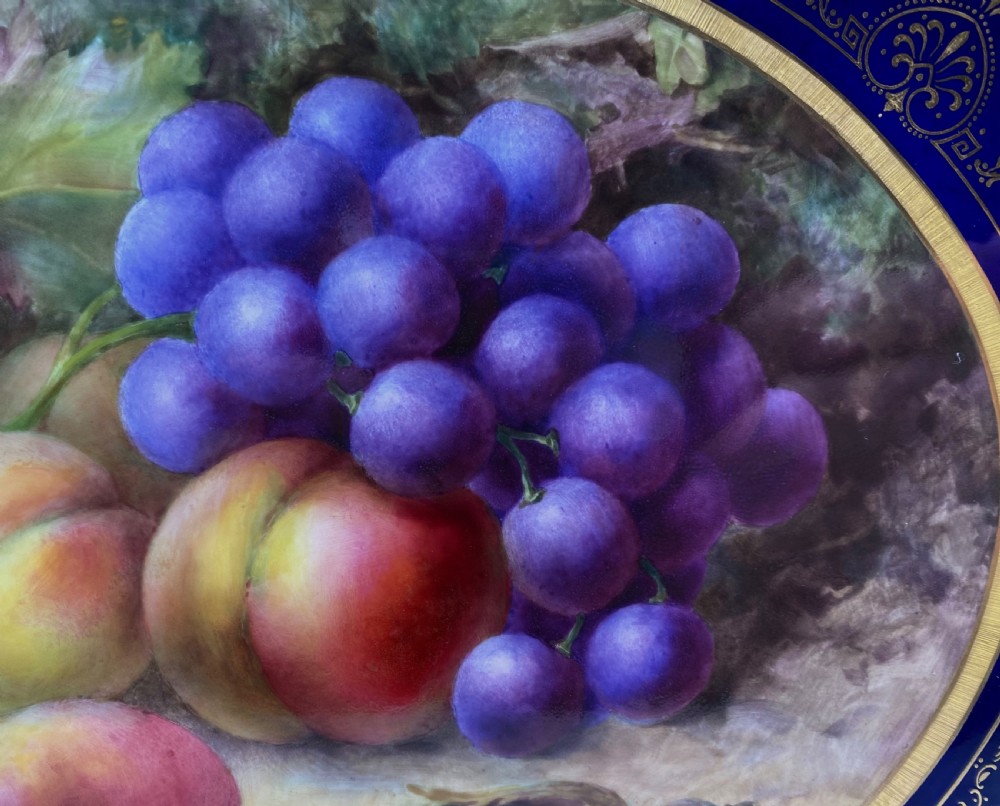 A square Royal Worcester porcelain tray featuring a central oval hand-painted fruit study framed by a dark cobalt blue ground with gold tooling and a pierced gilt scrollwork border. View III