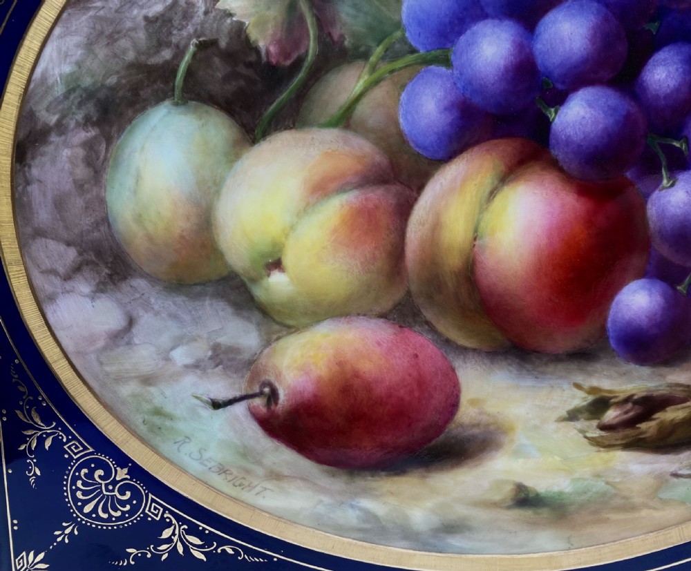 A square Royal Worcester porcelain tray featuring a central oval hand-painted fruit study framed by a dark cobalt blue ground with gold tooling and a pierced gilt scrollwork border. View IV