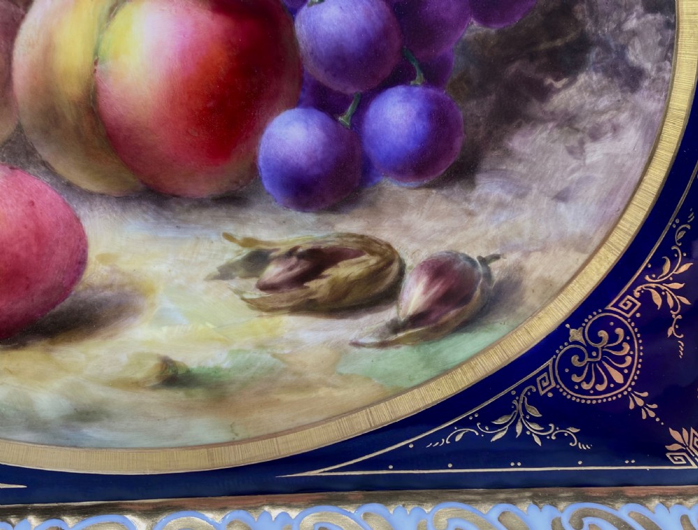 A square Royal Worcester porcelain tray featuring a central oval hand-painted fruit study framed by a dark cobalt blue ground with gold tooling and a pierced gilt scrollwork border. View VIII