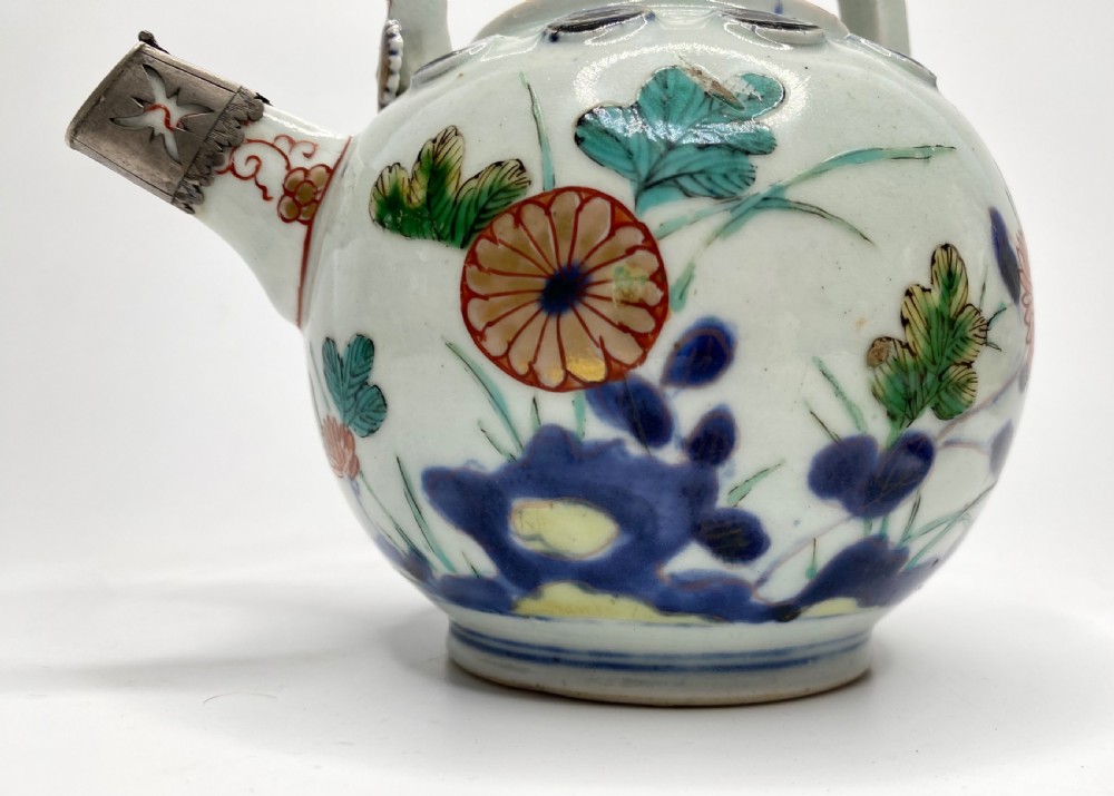 An Edo-period Japanese Imari porcelain sake ewer featuring polychrome floral enamel patterns, an overhead handle, and metal mounts. View IX