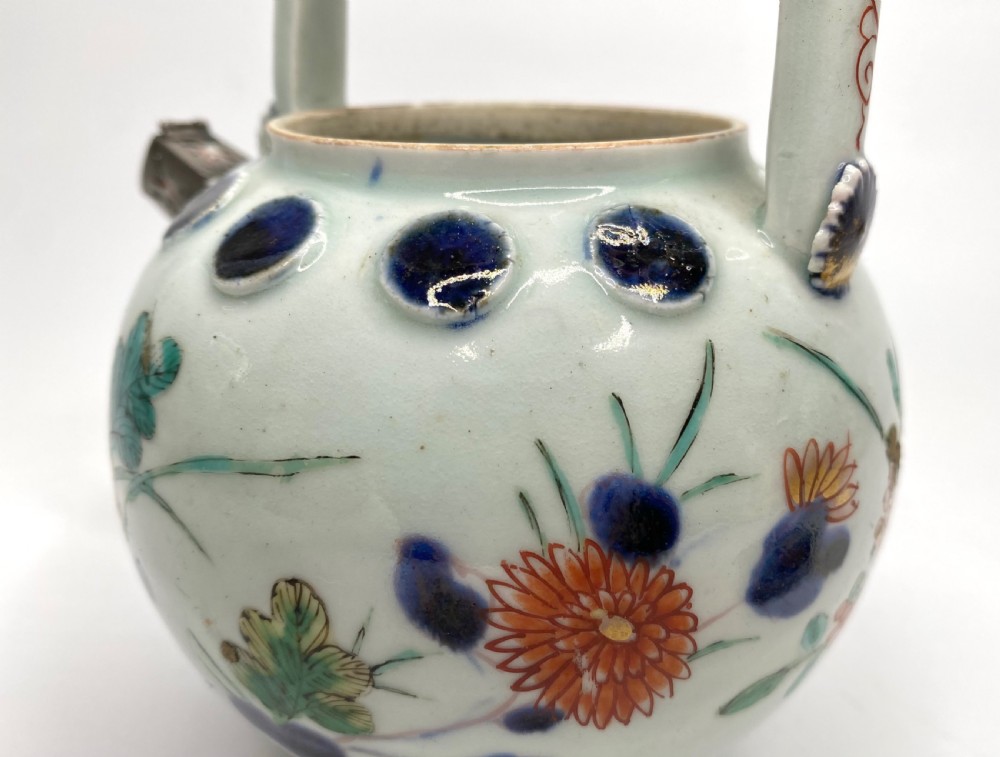 An Edo-period Japanese Imari porcelain sake ewer featuring polychrome floral enamel patterns, an overhead handle, and metal mounts. View XI