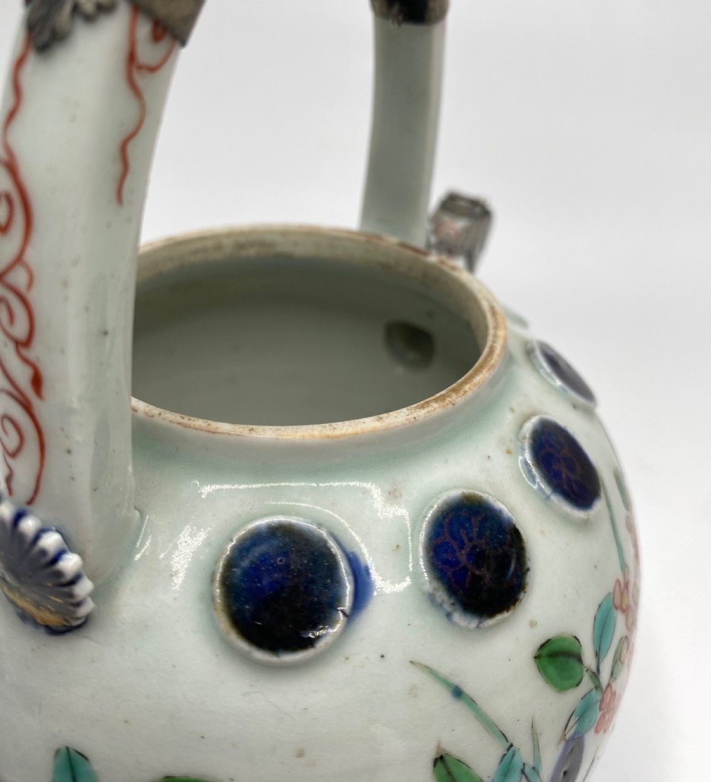 An Edo-period Japanese Imari porcelain sake ewer featuring polychrome floral enamel patterns, an overhead handle, and metal mounts. View XV