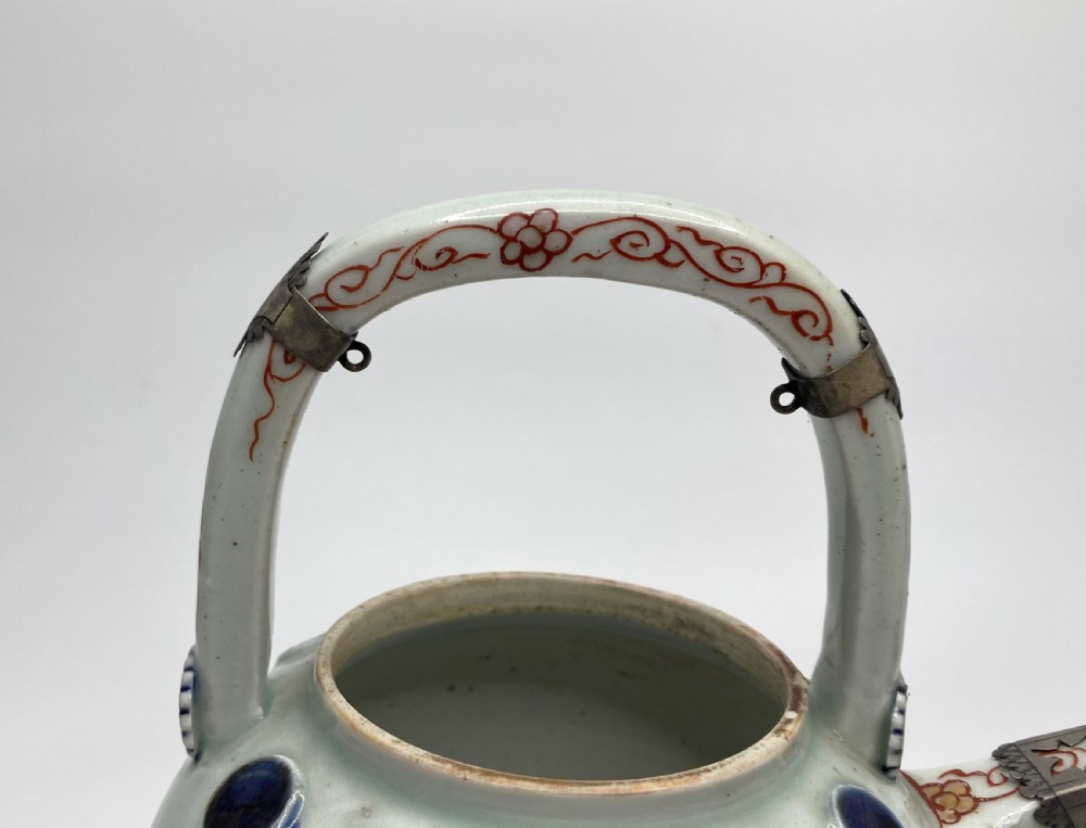 An Edo-period Japanese Imari porcelain sake ewer featuring polychrome floral enamel patterns, an overhead handle, and metal mounts. View XVII
