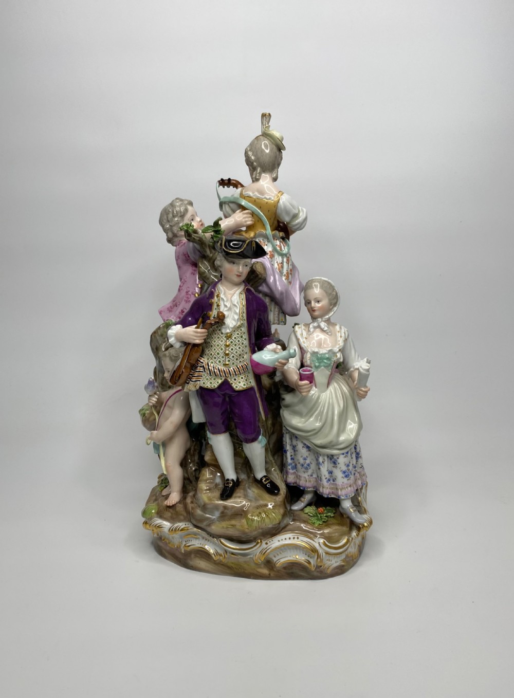 A 19th-century Meissen polychrome porcelain figural group depicting musicians dressed in 18th-century attire gathered around a central column.
