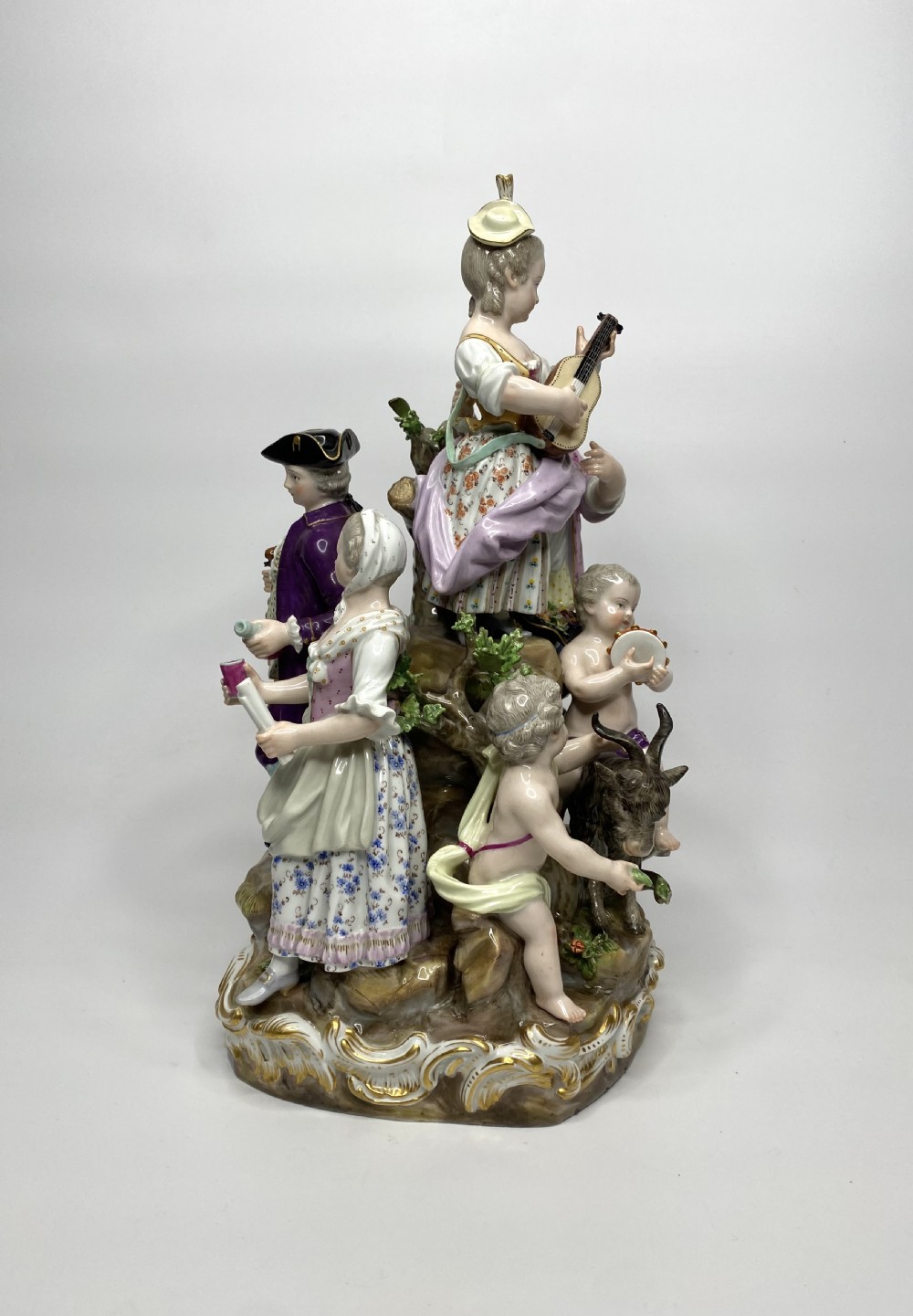 A 19th-century Meissen polychrome porcelain figural group depicting musicians dressed in 18th-century attire gathered around a central column. View II