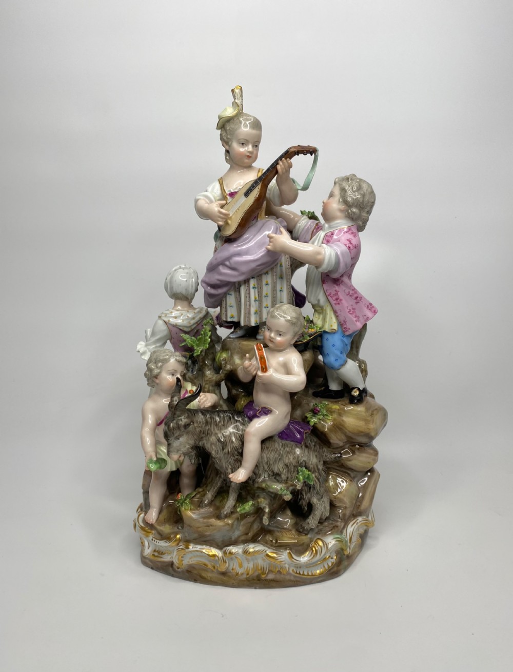 A 19th-century Meissen polychrome porcelain figural group depicting musicians dressed in 18th-century attire gathered around a central column. View III
