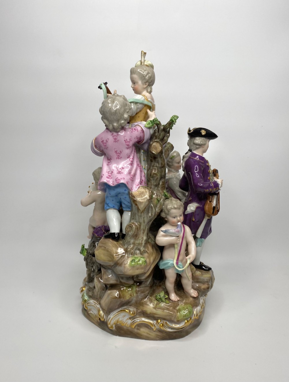 A 19th-century Meissen polychrome porcelain figural group depicting musicians dressed in 18th-century attire gathered around a central column. View IV