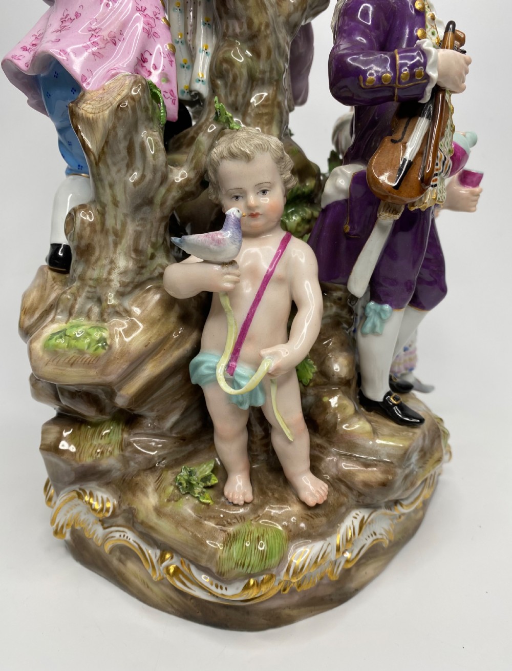 A 19th-century Meissen polychrome porcelain figural group depicting musicians dressed in 18th-century attire gathered around a central column. View V