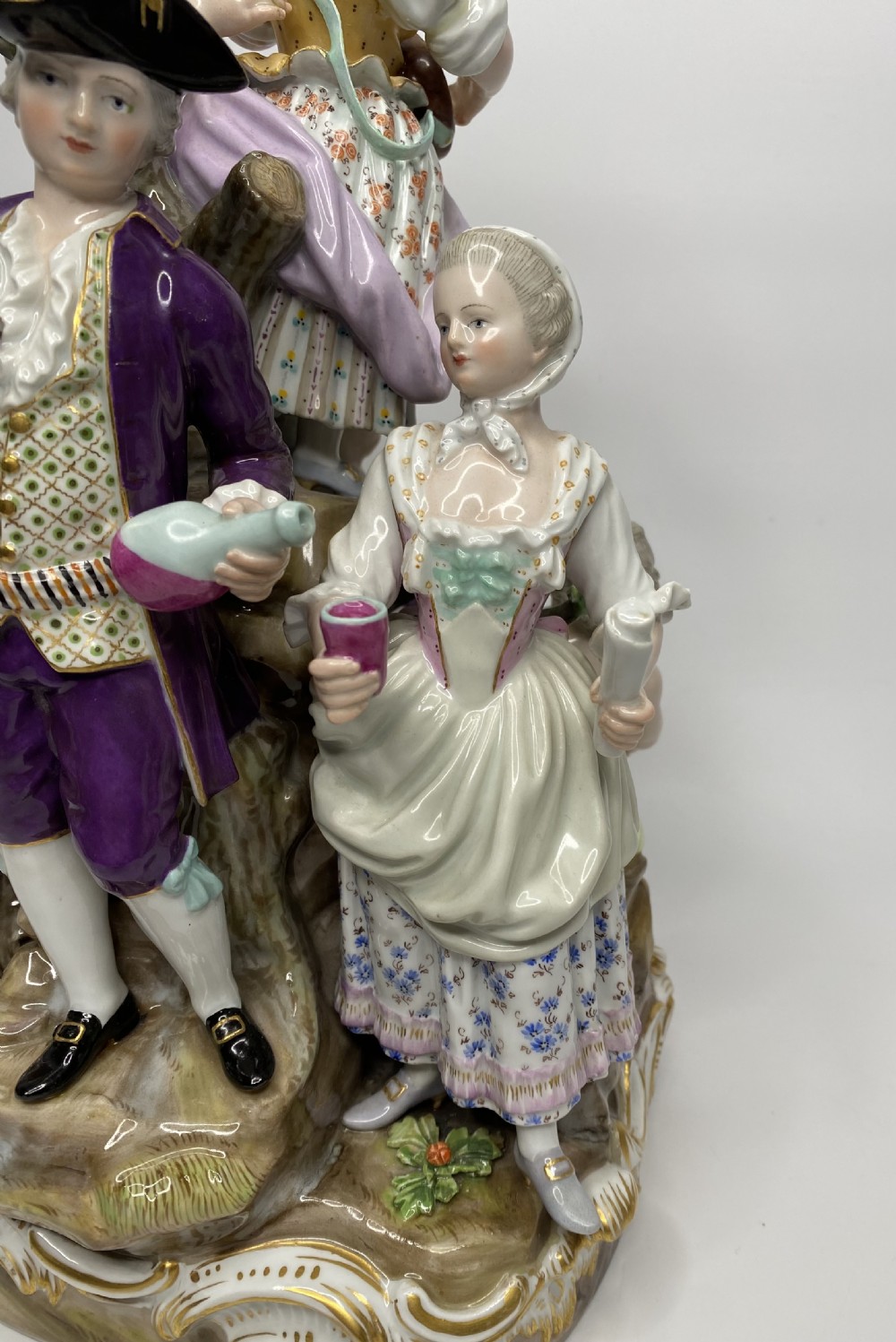 A 19th-century Meissen polychrome porcelain figural group depicting musicians dressed in 18th-century attire gathered around a central column. View VI