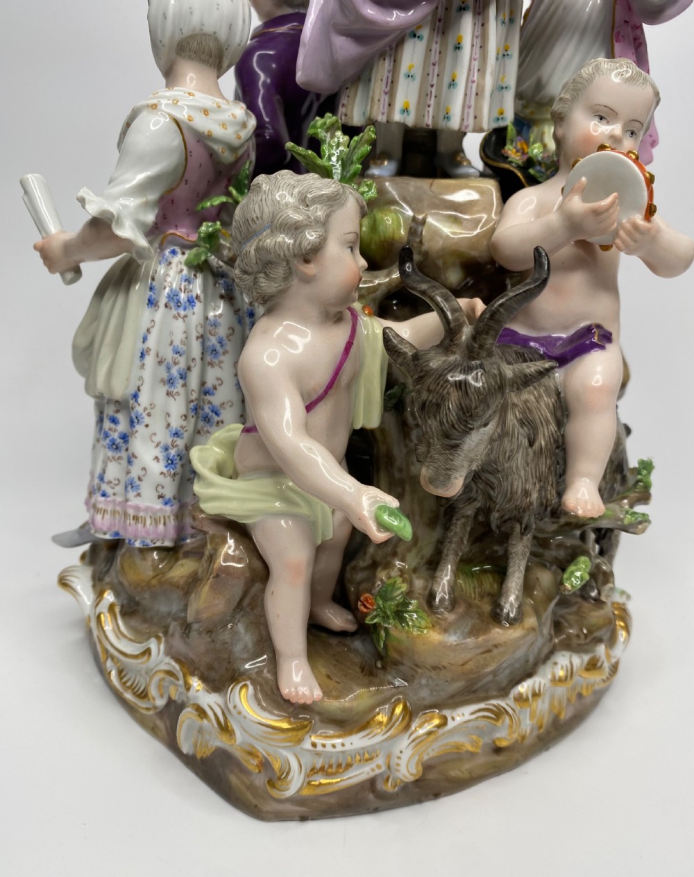 A 19th-century Meissen polychrome porcelain figural group depicting musicians dressed in 18th-century attire gathered around a central column. View VIII