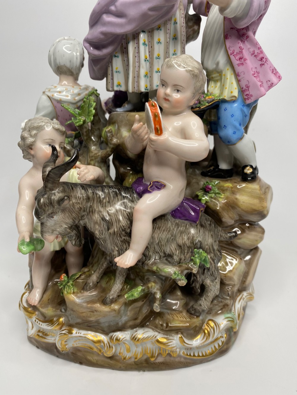 A 19th-century Meissen polychrome porcelain figural group depicting musicians dressed in 18th-century attire gathered around a central column. View X