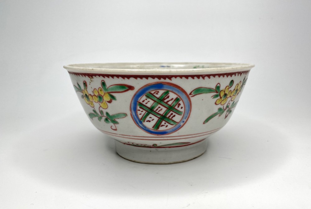 A Chinese Swatow porcelain bowl decorated with red, green, and yellow floral motifs and roundels on an off-white background. View II