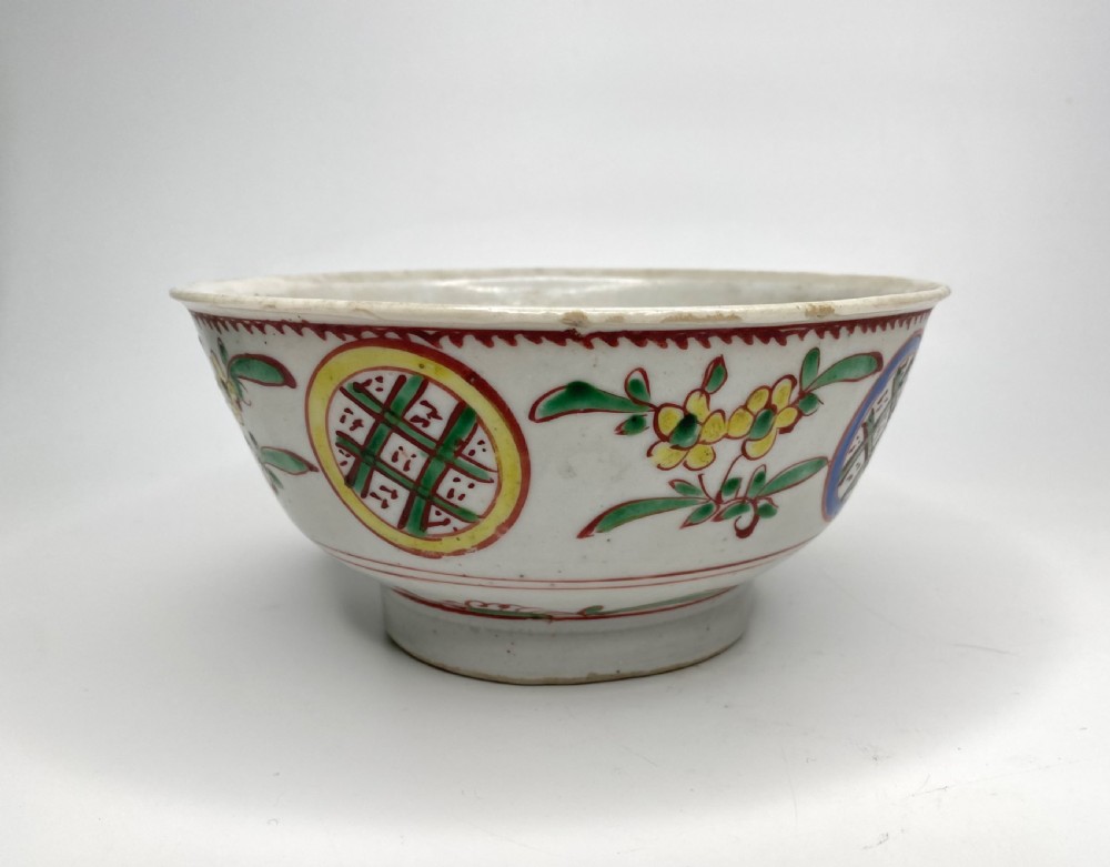 A Chinese Swatow porcelain bowl decorated with red, green, and yellow floral motifs and roundels on an off-white background. View III
