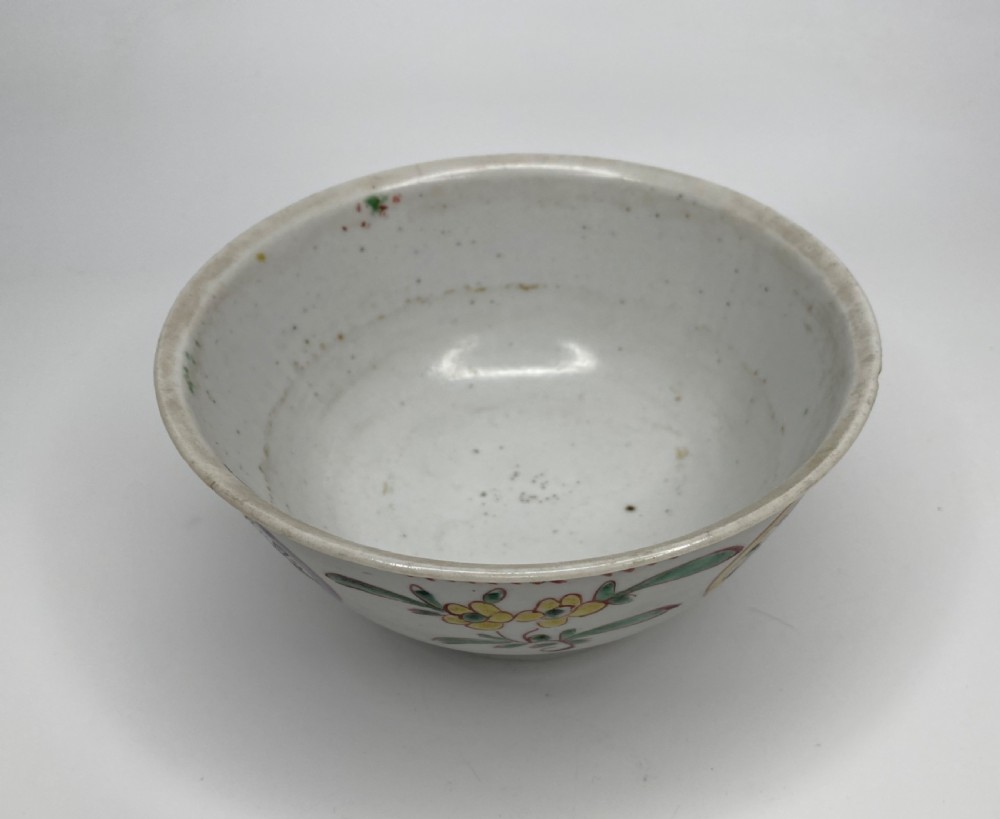 A Chinese Swatow porcelain bowl decorated with red, green, and yellow floral motifs and roundels on an off-white background. View VI