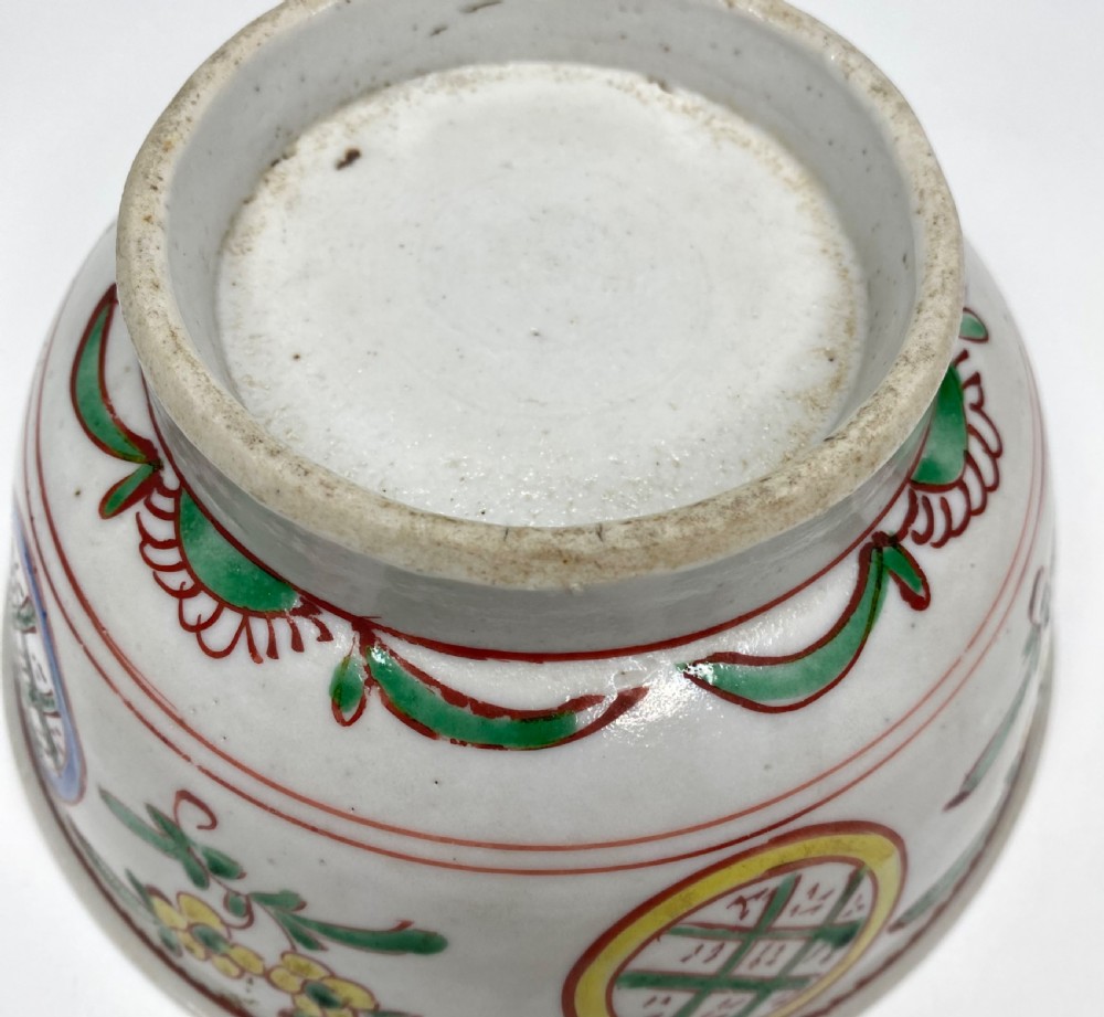 A Chinese Swatow porcelain bowl decorated with red, green, and yellow floral motifs and roundels on an off-white background. View VII
