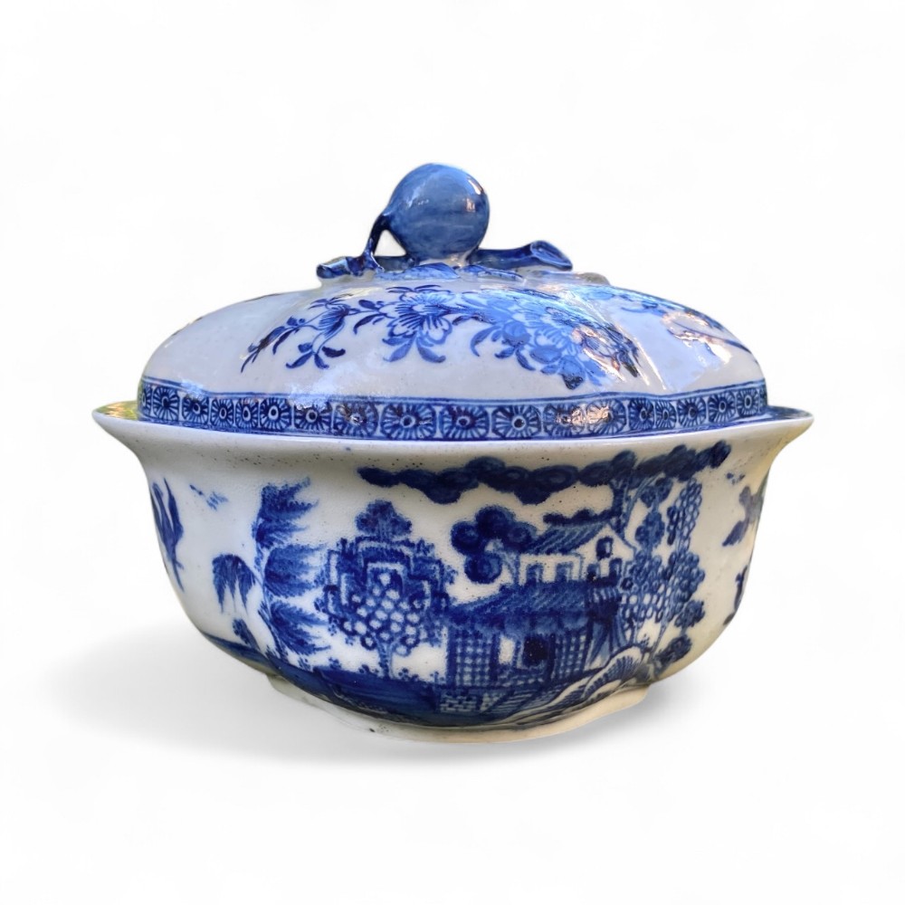 An eighteenth-century Derby blue and white porcelain tureen and fitted cover featuring hand-painted chinoiserie landscape decoration and a sculptural finial.