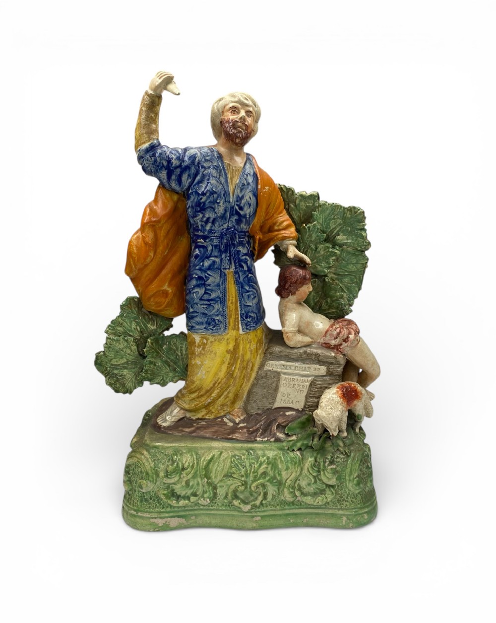 A polychrome Staffordshire earthenware figure group depicting Abraham and Isaac on a green leaf-moulded ceramic base.