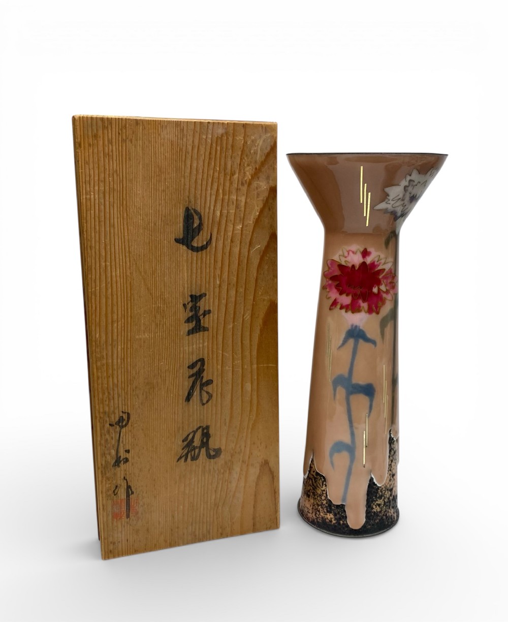 A tall Japanese Showa period cloisonne enamel vase with a flared rim, displaying a pink flower motif on a beige background next to its wooden box.
