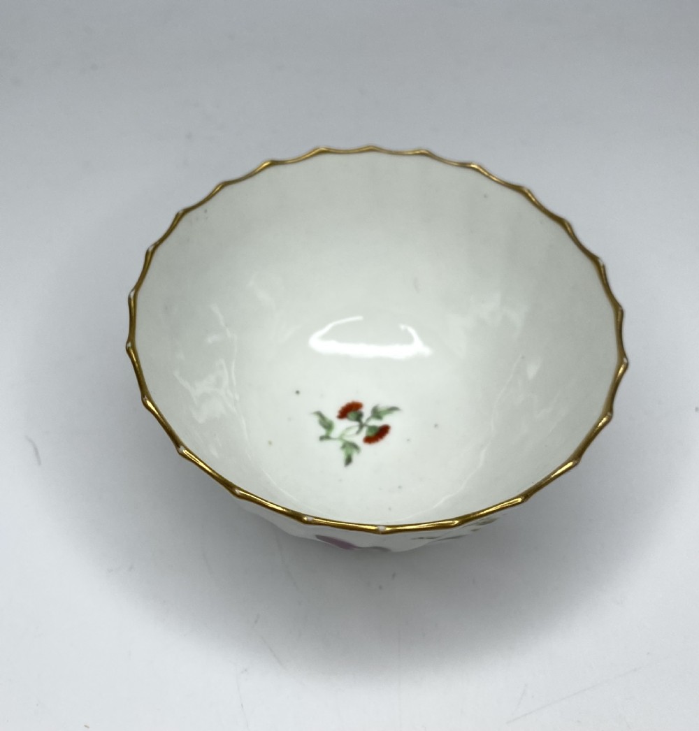 An 18th-century Worcester porcelain tea trio comprising a teacup, tea bowl, and saucer with hand-painted floral sprays and gilded spiralled moulding. View XVI
