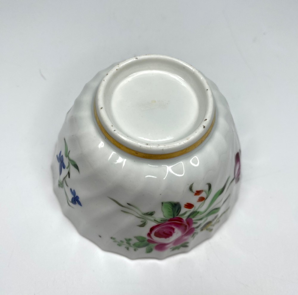 An 18th-century Worcester porcelain tea trio comprising a teacup, tea bowl, and saucer with hand-painted floral sprays and gilded spiralled moulding. View XVII