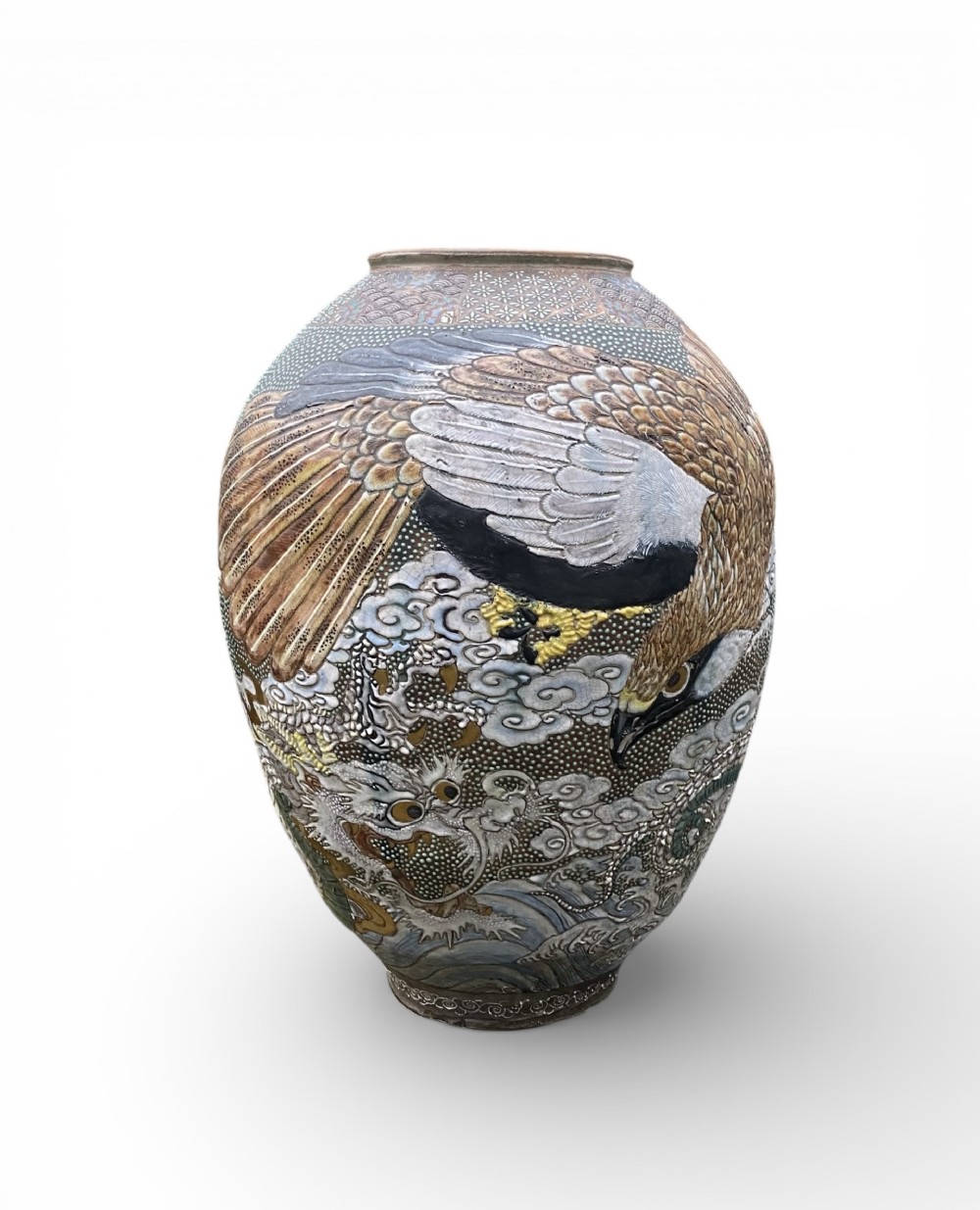 A Japanese Meiji period stoneware vase featuring detailed polychrome enamel relief of an eagle and a dragon amongst clouds.