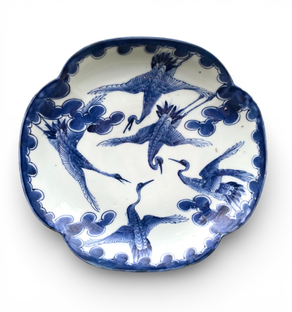 An eighteenth-century lobed Arita porcelain dish decorated with five flying cranes in cobalt blue underglaze against a white background.
