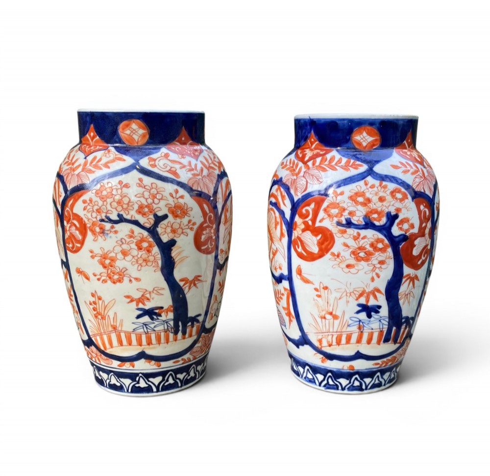 A pair of Japanese Imari porcelain baluster-shaped vases decorated with hand-painted floral patterns in cobalt blue and iron-red enamel on a white ground.