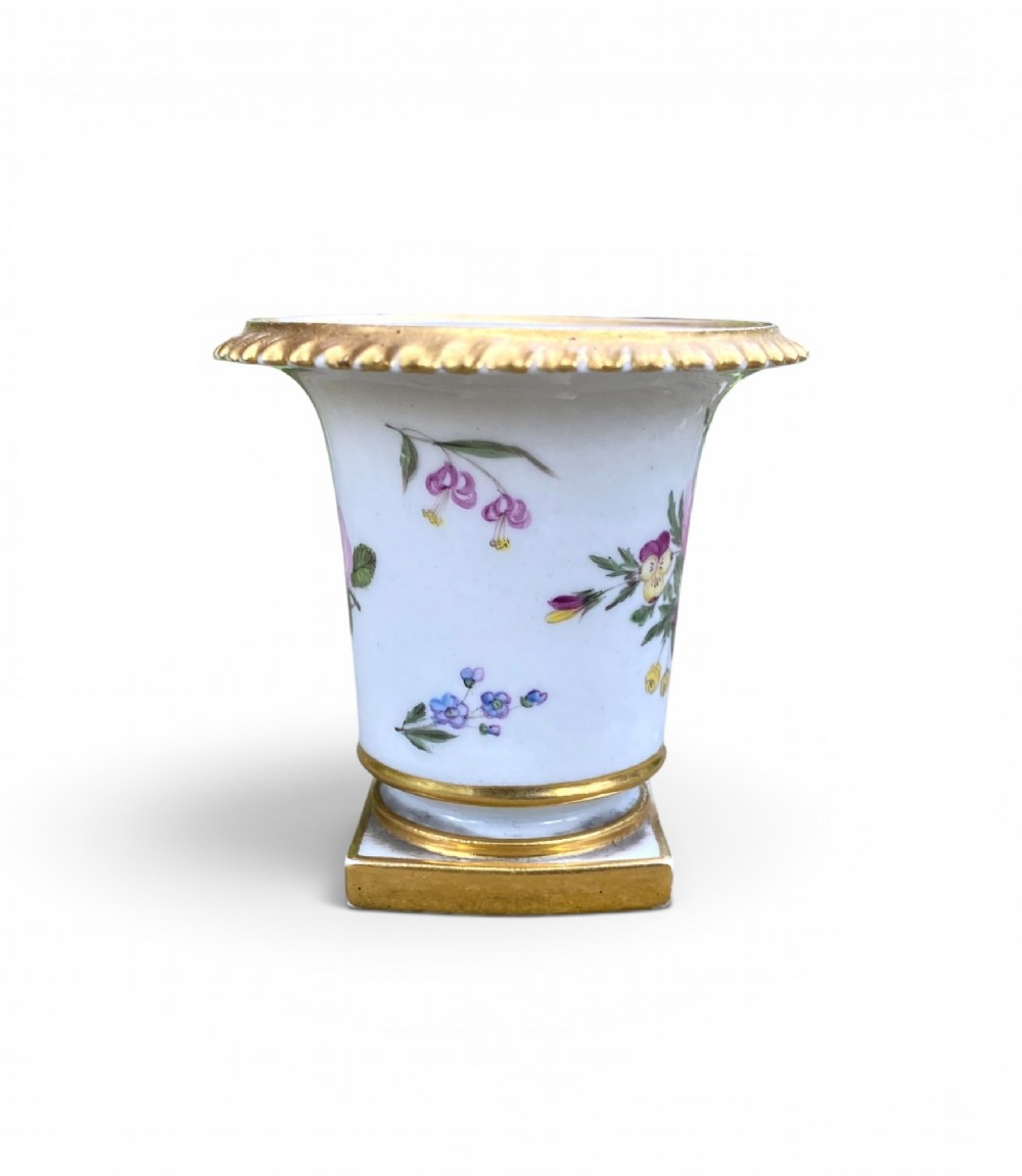 A flared white antique porcelain vase decorated with hand-painted pink and purple flowers and a square gilded pedestal base. View II