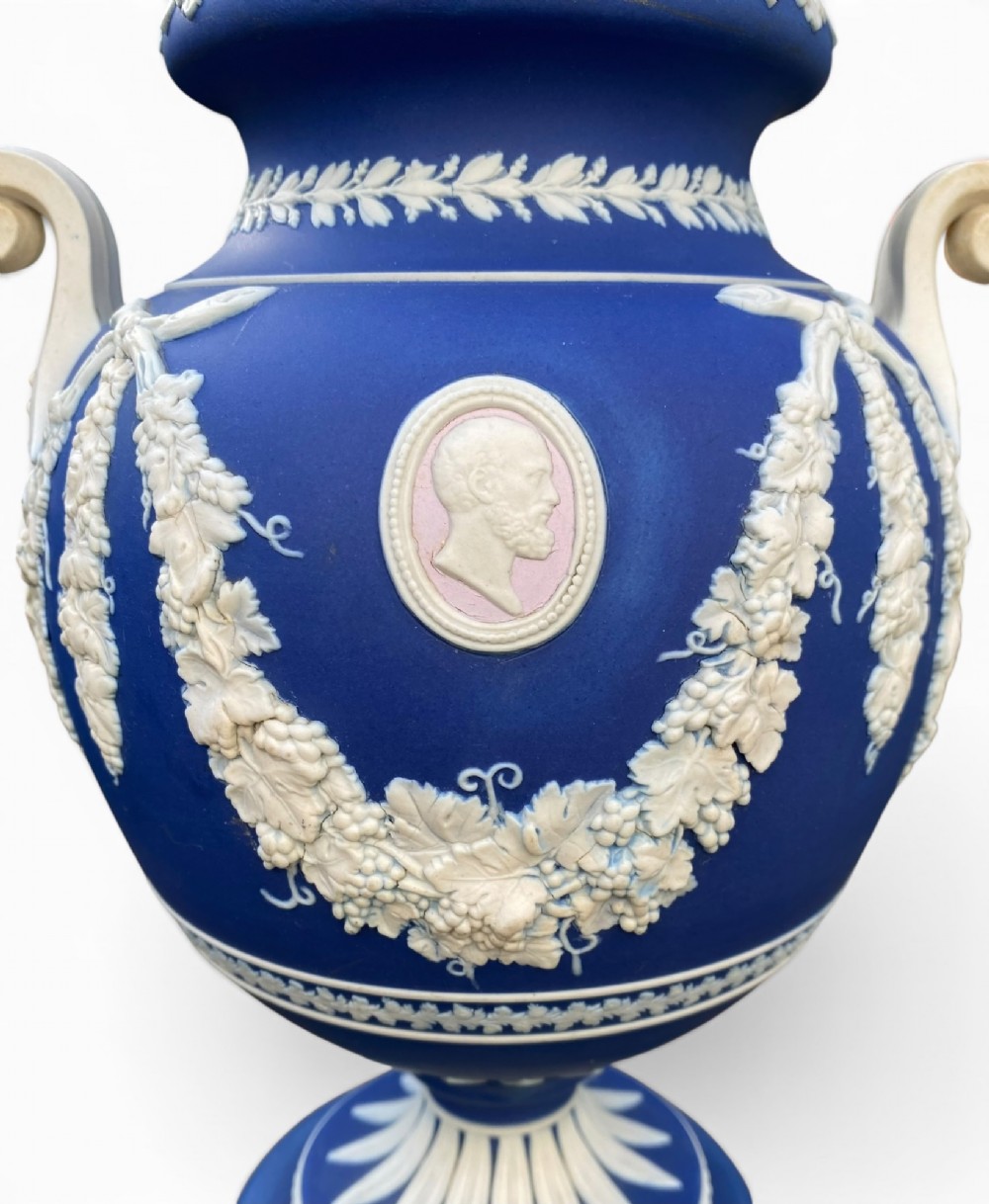 A cobalt blue jasperware pot pourri urn on a matching cylindrical pedestal, featuring white raised relief swags, classical medallions, scroll handles, and a pierced lid. View II