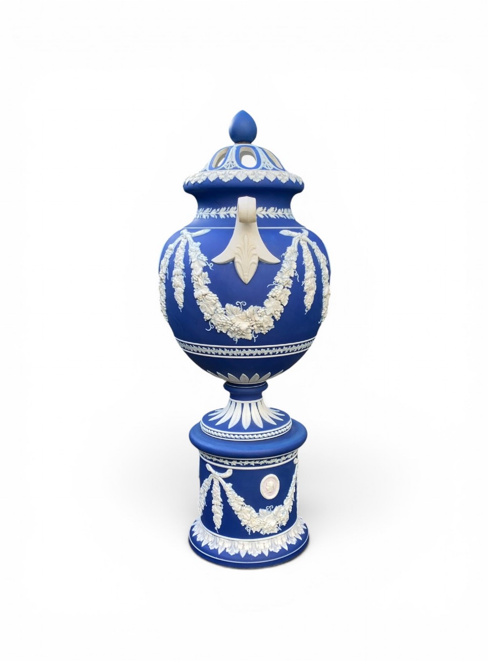 A cobalt blue jasperware pot pourri urn on a matching cylindrical pedestal, featuring white raised relief swags, classical medallions, scroll handles, and a pierced lid. View III
