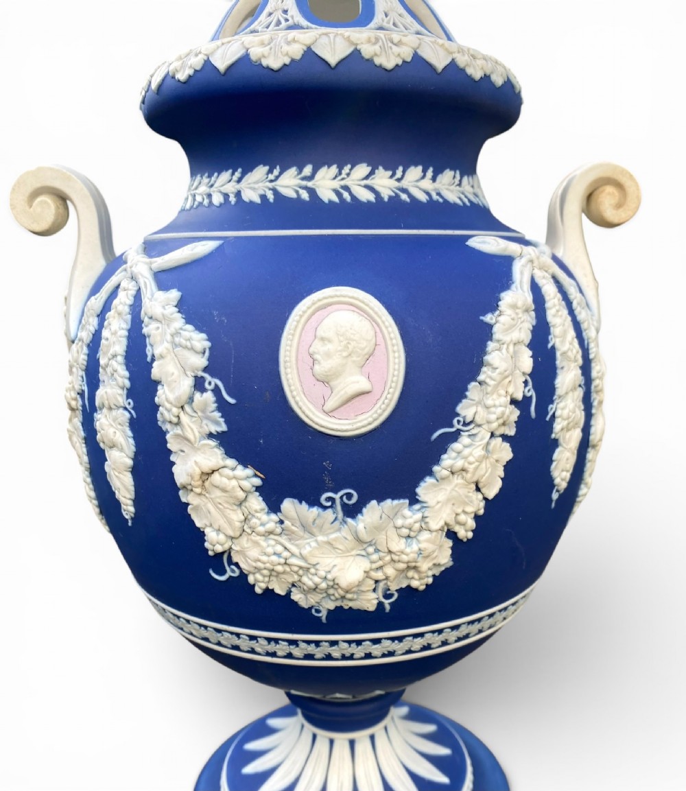 A cobalt blue jasperware pot pourri urn on a matching cylindrical pedestal, featuring white raised relief swags, classical medallions, scroll handles, and a pierced lid. View V