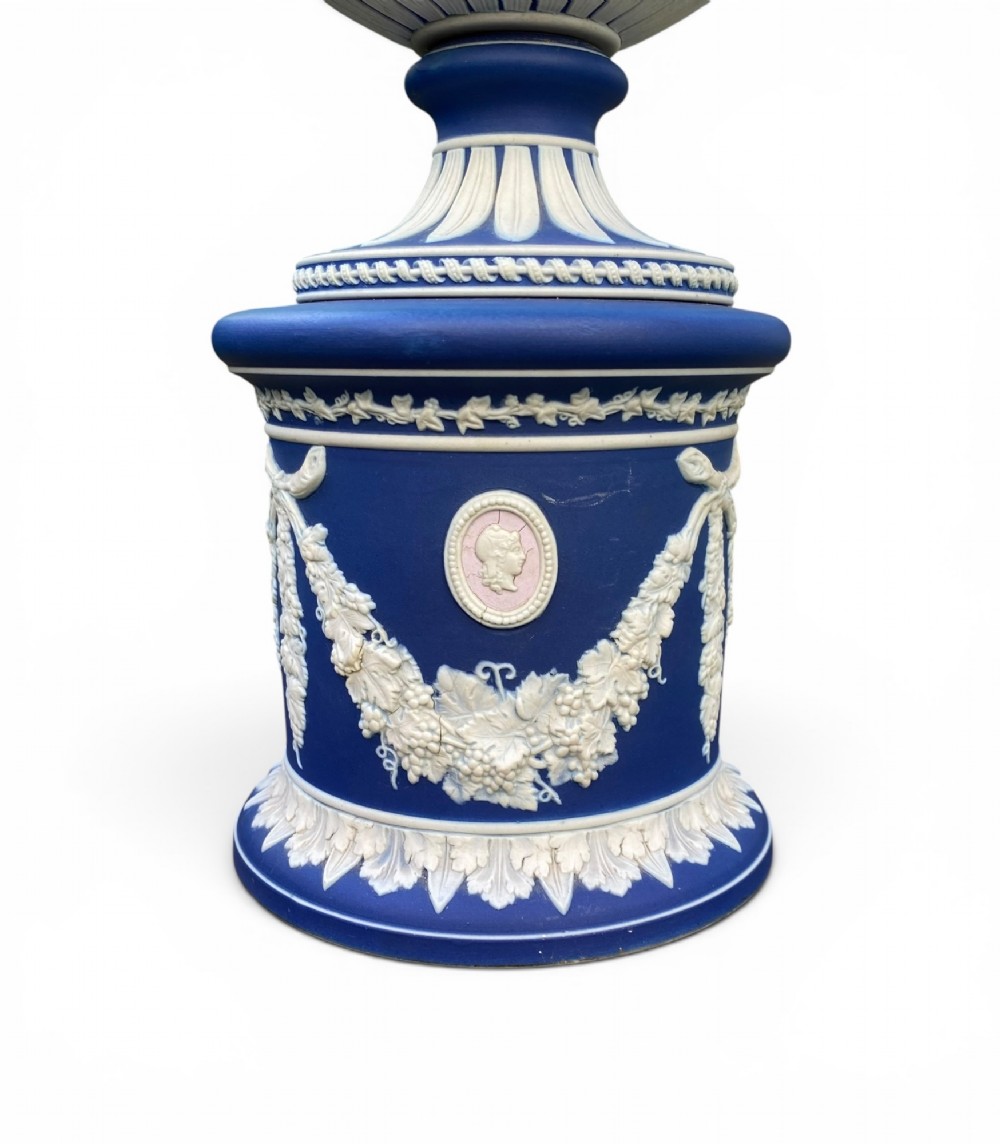 A cobalt blue jasperware pot pourri urn on a matching cylindrical pedestal, featuring white raised relief swags, classical medallions, scroll handles, and a pierced lid. View VII
