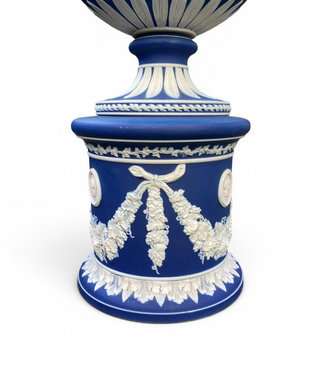 A cobalt blue jasperware pot pourri urn on a matching cylindrical pedestal, featuring white raised relief swags, classical medallions, scroll handles, and a pierced lid. View VIII