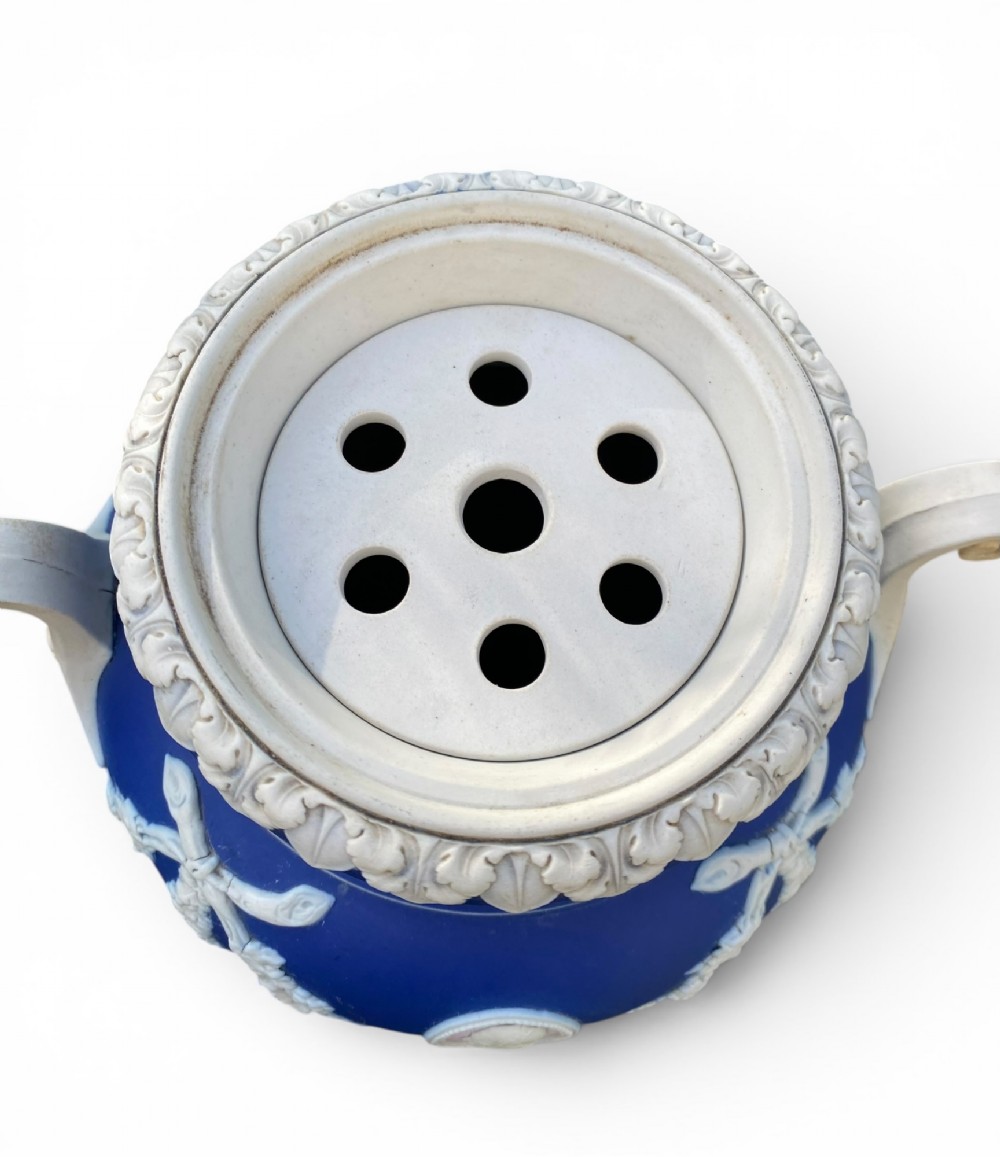 A cobalt blue jasperware pot pourri urn on a matching cylindrical pedestal, featuring white raised relief swags, classical medallions, scroll handles, and a pierced lid. View IX