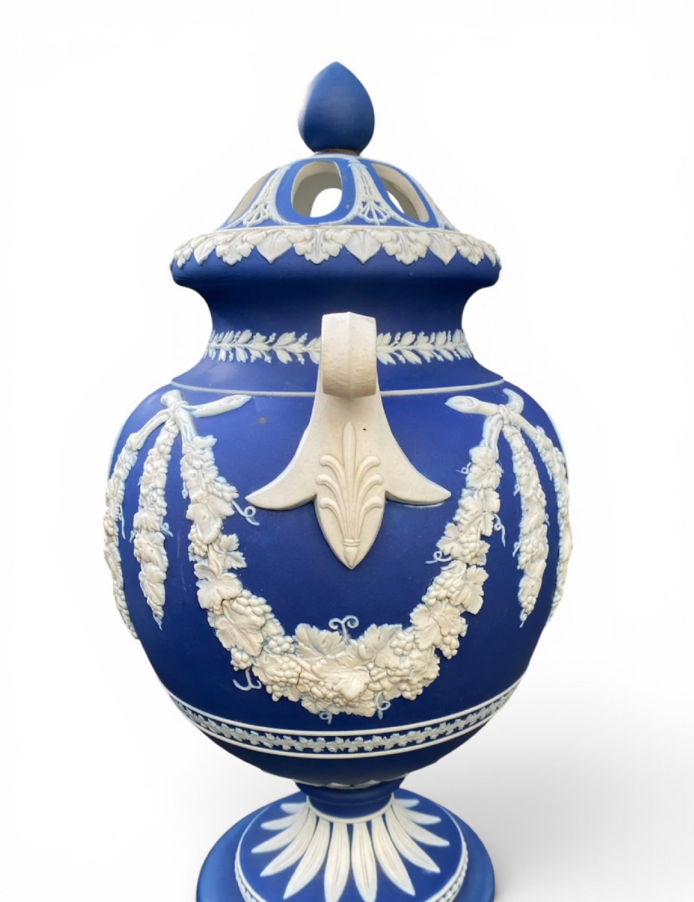 A cobalt blue jasperware pot pourri urn on a matching cylindrical pedestal, featuring white raised relief swags, classical medallions, scroll handles, and a pierced lid. View XV