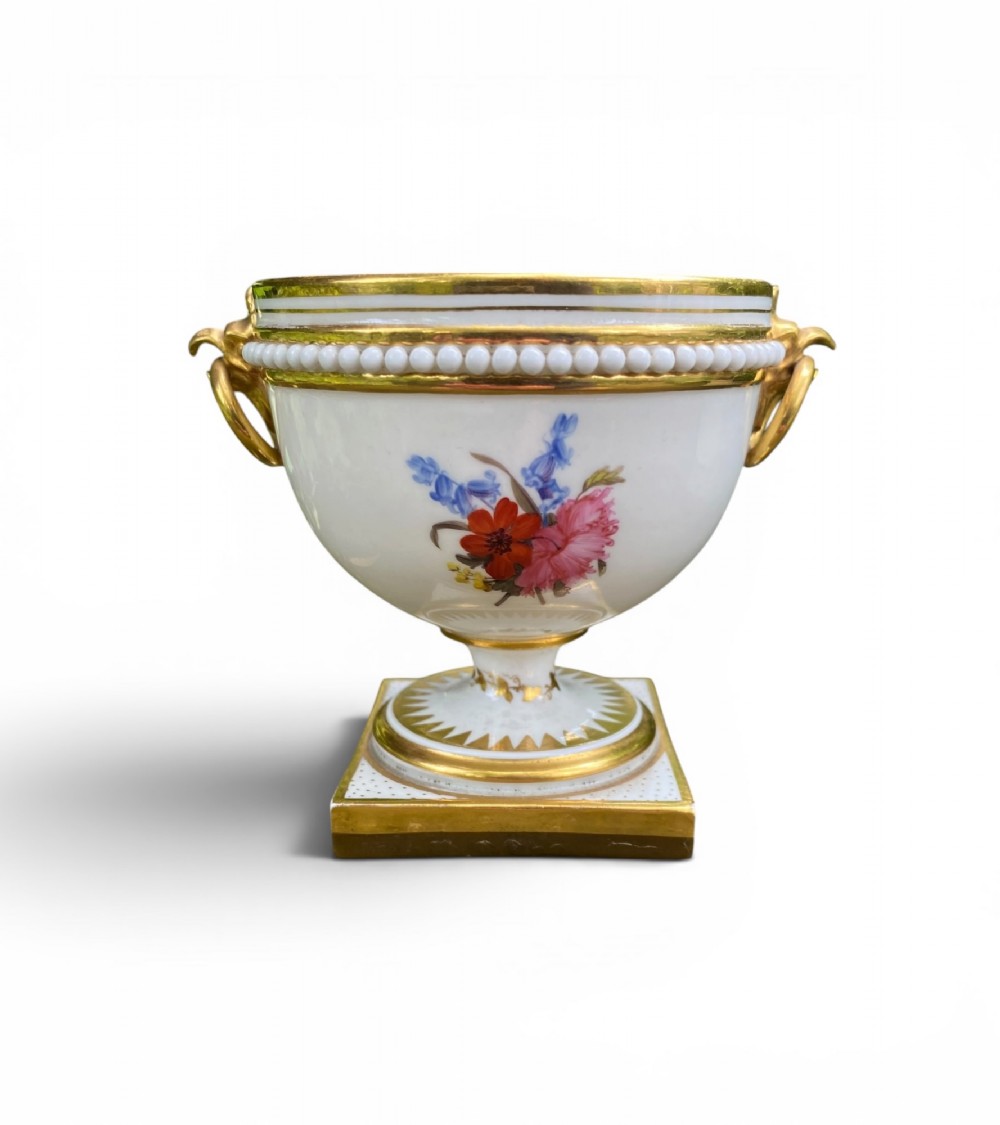 A Regency period white porcelain urn featuring hand-painted botanical blooms, twin gilt handles, a row of pearl-like beaded trimming around the rim, and a gilded square plinth base. View III