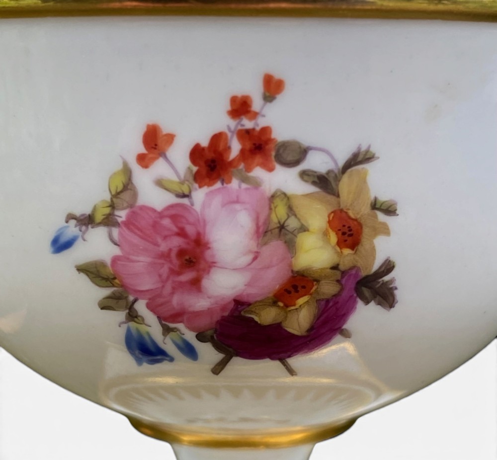 A Regency period white porcelain urn featuring hand-painted botanical blooms, twin gilt handles, a row of pearl-like beaded trimming around the rim, and a gilded square plinth base. View VI
