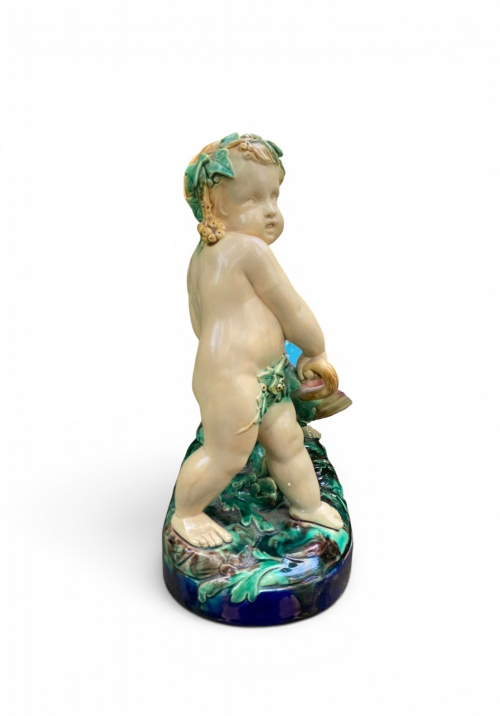 A Victorian Minton majolica centrepiece featuring two cherub figures supporting a shell-shaped bowl with a bright turquoise interior on a green foliate base. View III