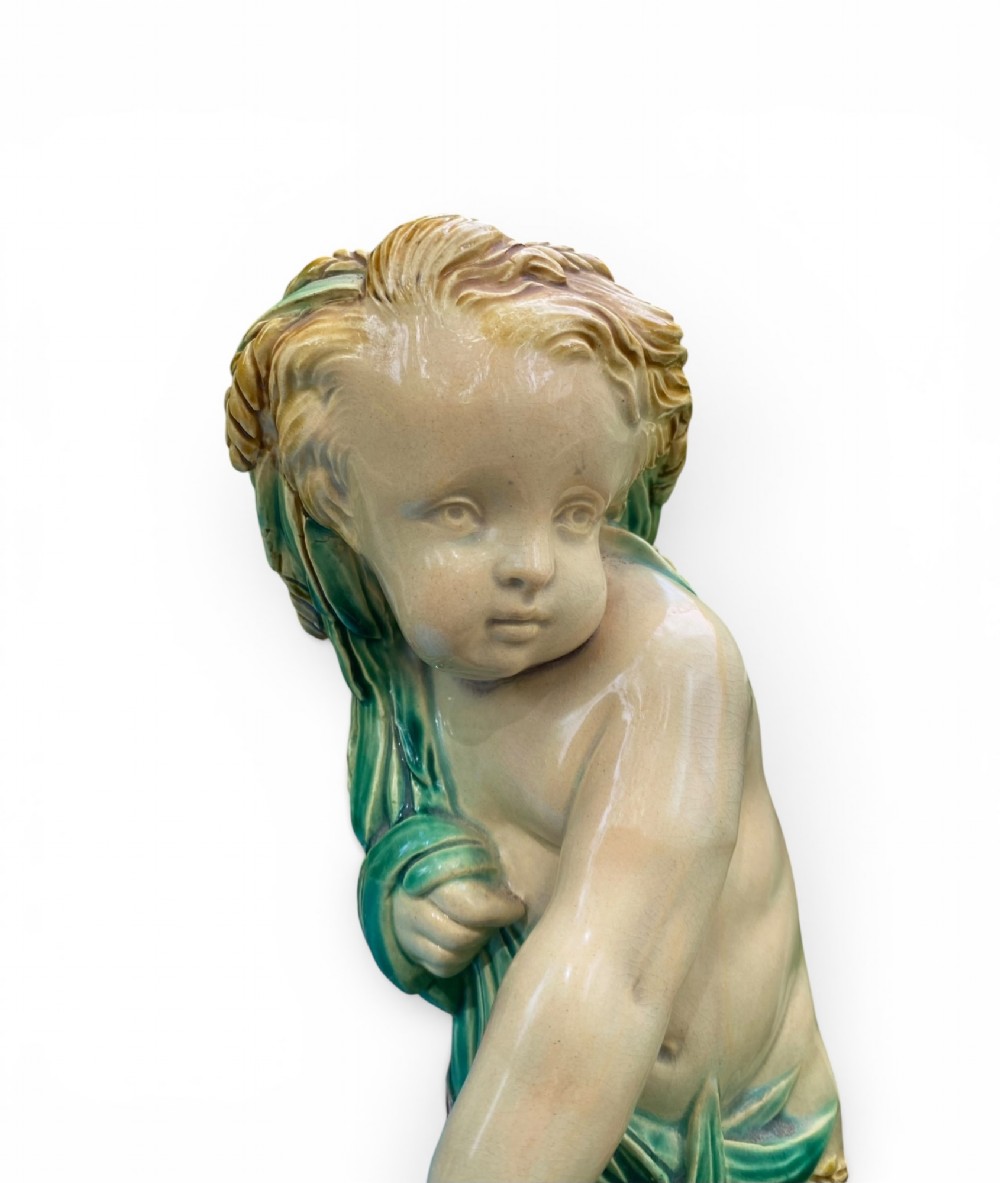 A Victorian Minton majolica centrepiece featuring two cherub figures supporting a shell-shaped bowl with a bright turquoise interior on a green foliate base. View VIII