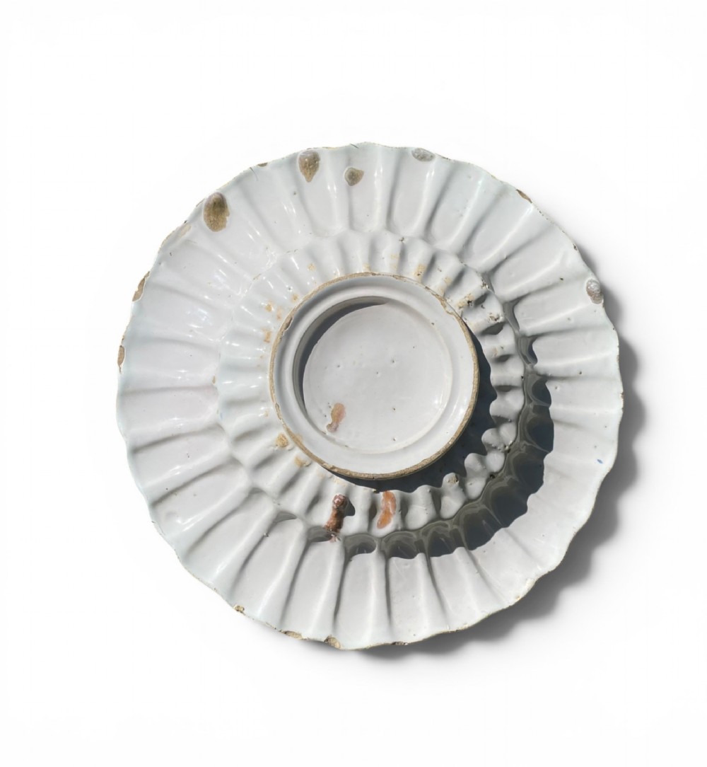 A circular antique Dutch Delft tin-glazed earthenware charger featuring hand-painted polychrome floral motifs in blue, yellow, and green across a fluted lobed rim and central basin. View IV