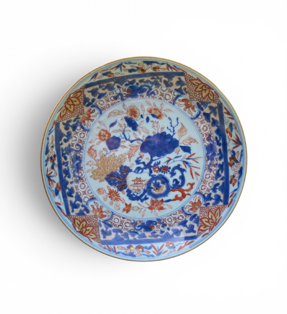 An 18th-century Chinese Imari porcelain dish decorated with underglaze cobalt blue foliage, iron-red enamel florals, and geometric diaper border patterns.