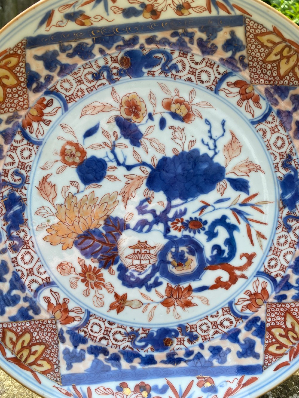 An 18th-century Chinese Imari porcelain dish decorated with underglaze cobalt blue foliage, iron-red enamel florals, and geometric diaper border patterns. View VI