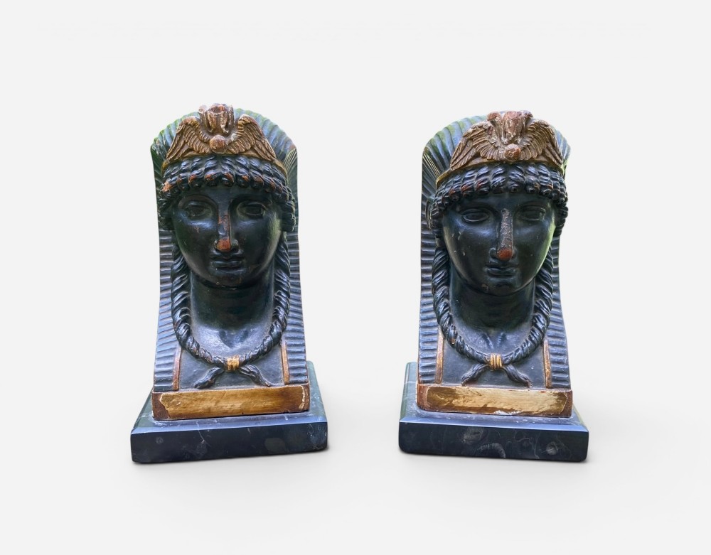 A facing pair of carved dark wood sphinx busts with gilt highlights mounted on rectangular black marble bases. View II