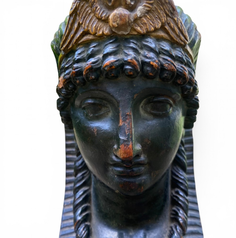 A facing pair of carved dark wood sphinx busts with gilt highlights mounted on rectangular black marble bases. View VIII
