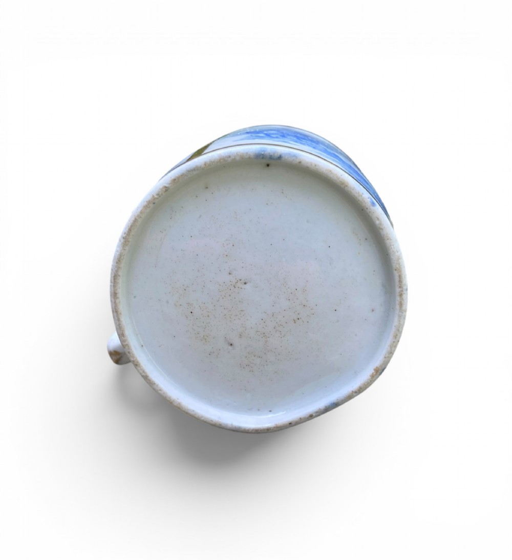 An antique blue and white porcelain coffee can and saucer featuring a painted landscape scene and gilded foliage borders. View VIII