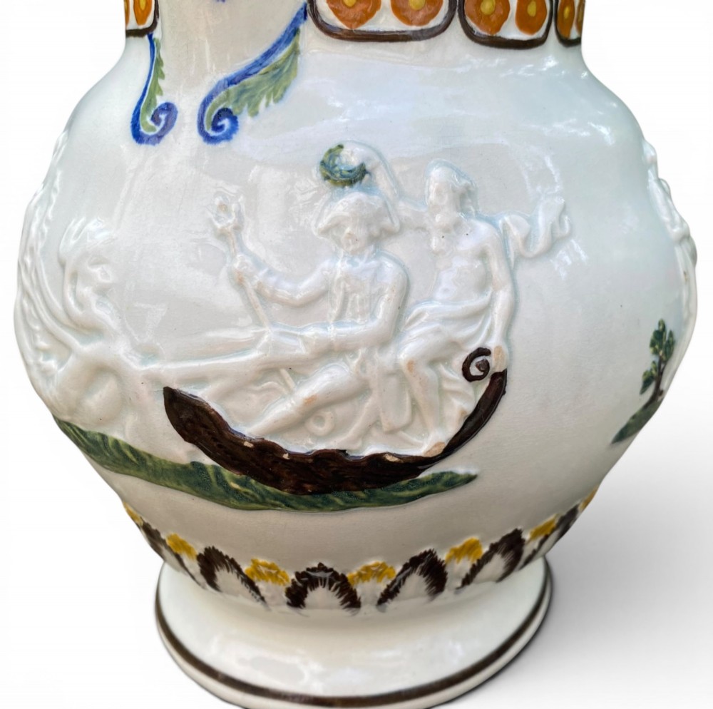 A late 18th-century relief-moulded Prattware ceramic jug featuring polychrome oxide highlights depicting naval battle motifs against an off-white background. View IV
